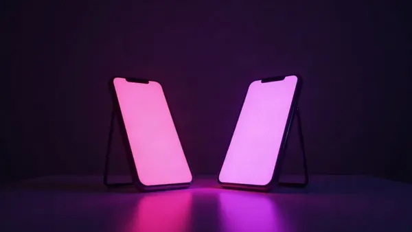 Twee smartphones tegenover elkaar op een donkere tafel, de ene roze, de andere paars (illustratie bij het artikel)